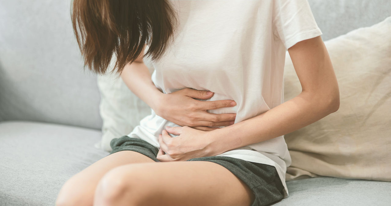 Frau, die sich aufgrund von Schmerzen den Bauch hält