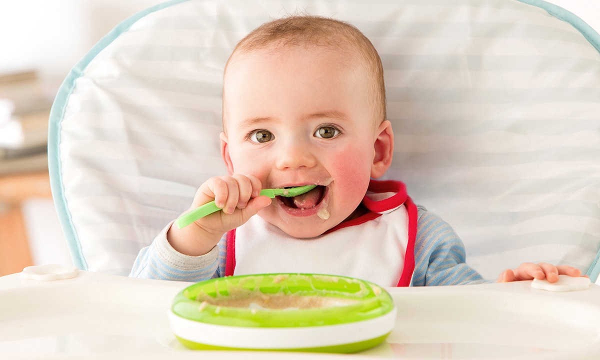 Baby isst selbst mit Löffel