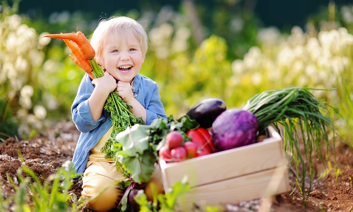 Lachendes Kind mit Gemüsekorb