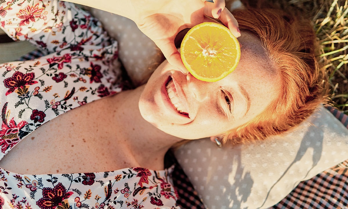 Frau mit Zitronenscheibe lächelt