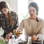 Zwei Frauen, die in der Küche stehen und gesund kochen