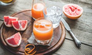 Ein Glas mit Grapefruitsaft und frische Grapefruits.