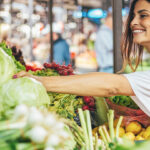 Frau kauft auf Markt Gemüse und Obst