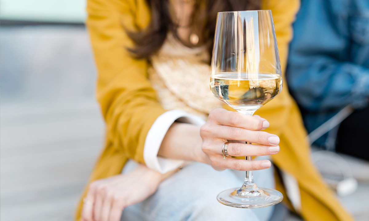 Frau hält ein Glas Weisswein in der Hand.