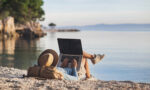 Mann arbeitet am Laptop am Strand