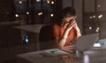 Verzweifelte und gestresste Frau sitzt nachts vor dem Laptop