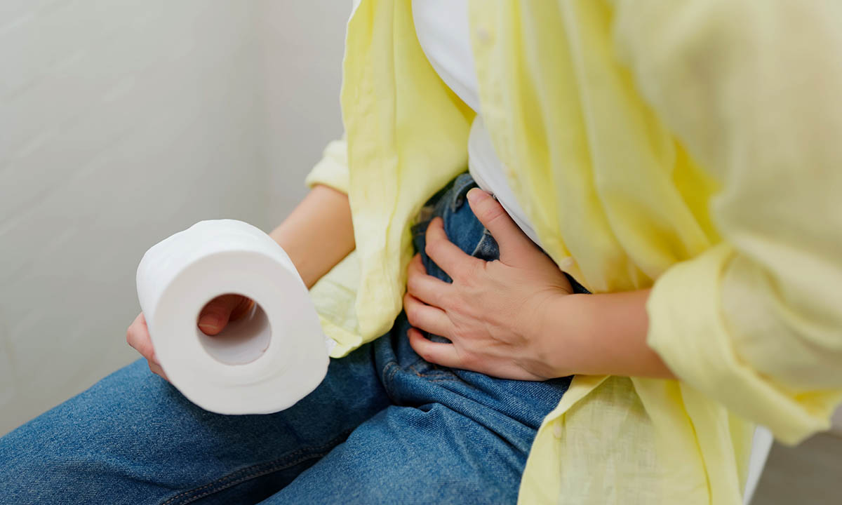 Frau sitzt auf der Toilette