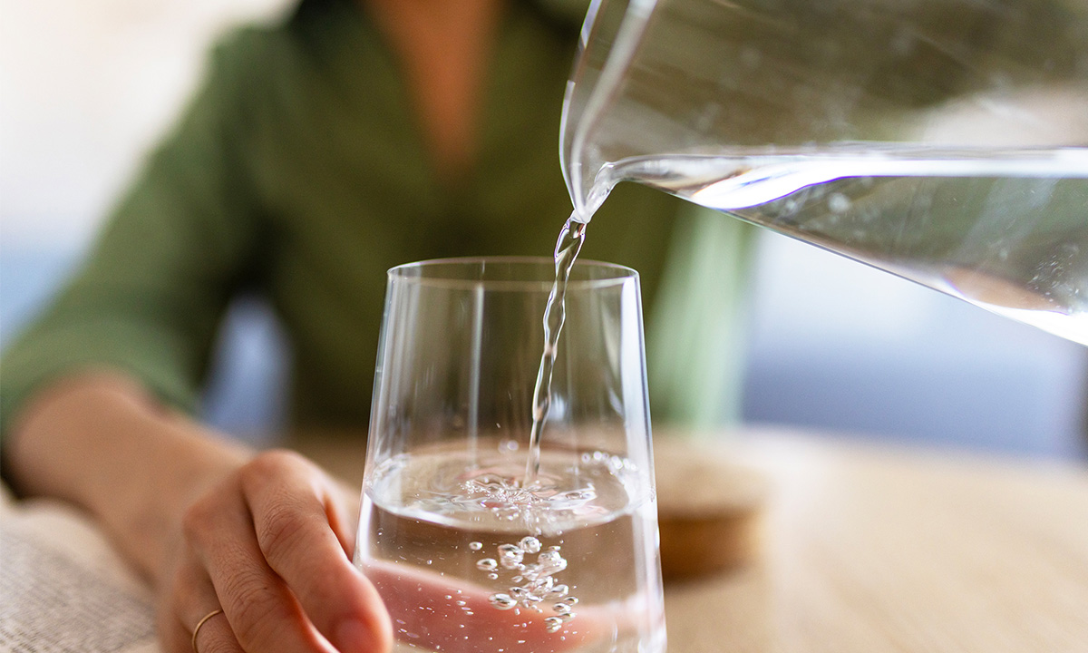 Wasser in ein Glas schenken
