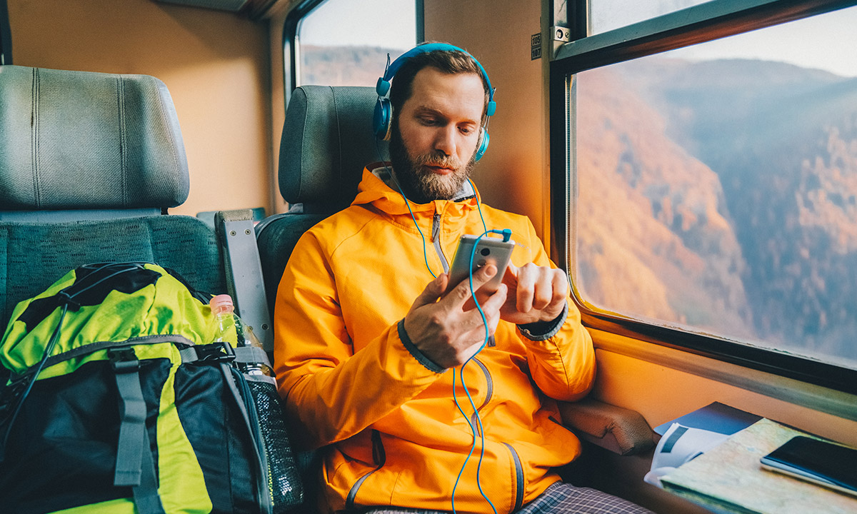 Mann sitzt im Zug und hört einen Podcast.