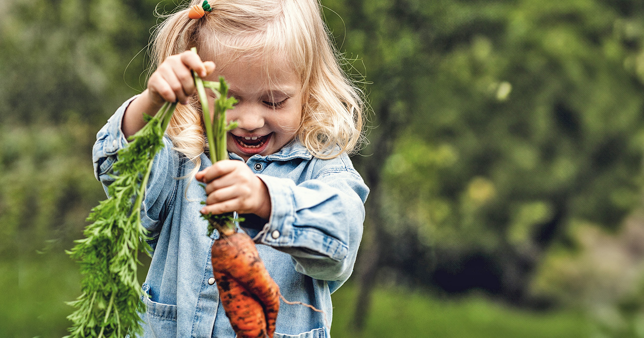 Kind hält Karotten: Ganzheitliche Kindergesundheit