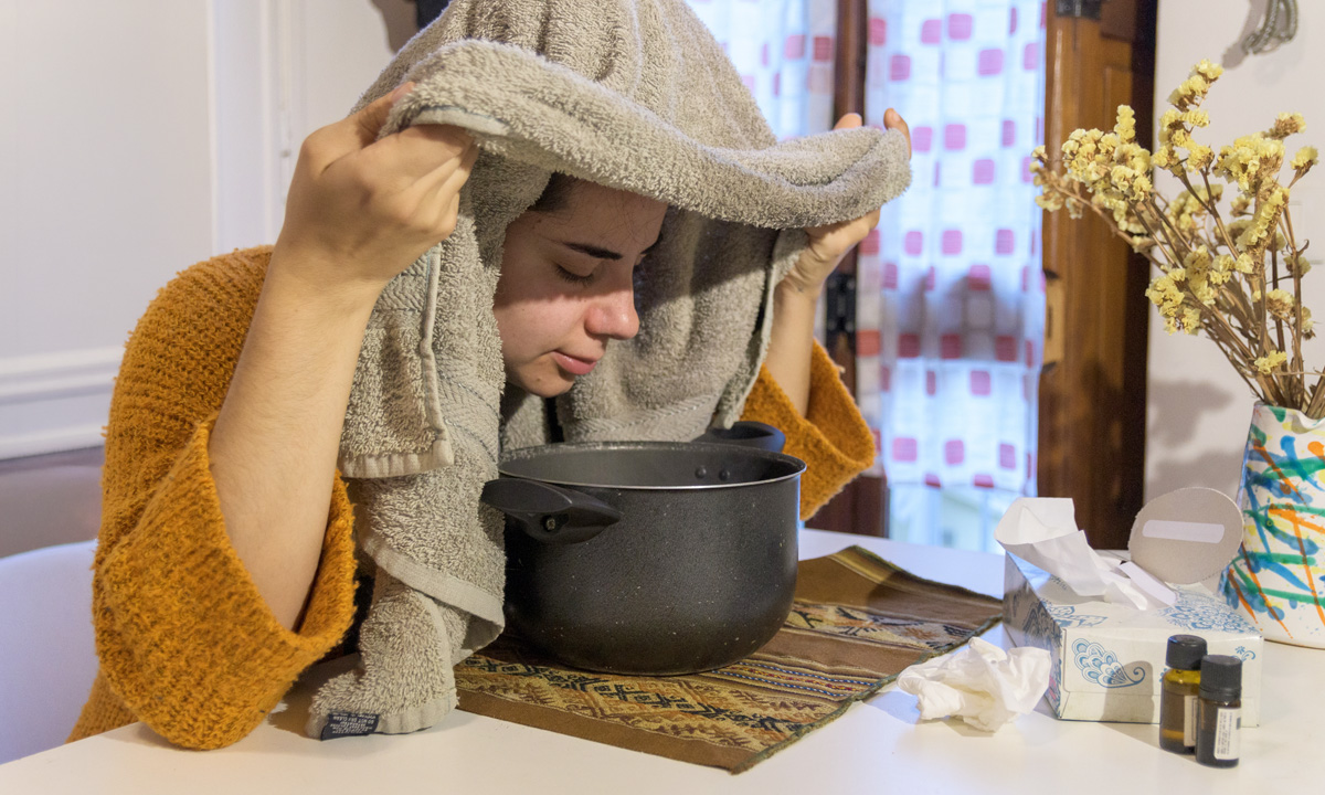 Frau inhalisiert mit Handtuch und Topf