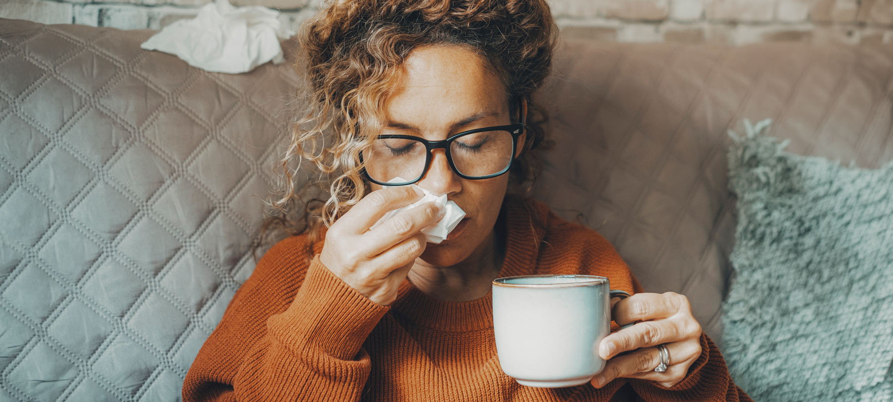 Frau mit Erkältung, Taschentuch und Teetasse