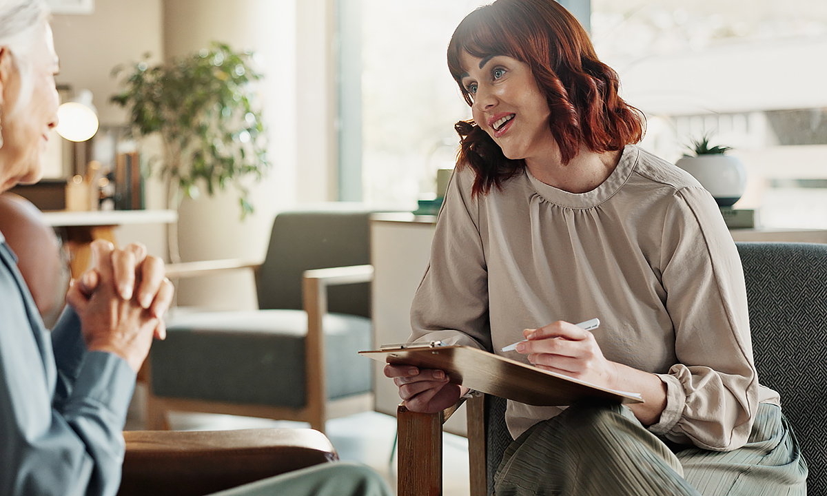Frau mit einem Notizblock in der Hand in einem Gespräch.