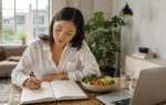 Frau führt ein Ernährungs- und Symptomtagebuch zu möglichen Unverträglichkeiten neben Laptop und Mahlzeit.